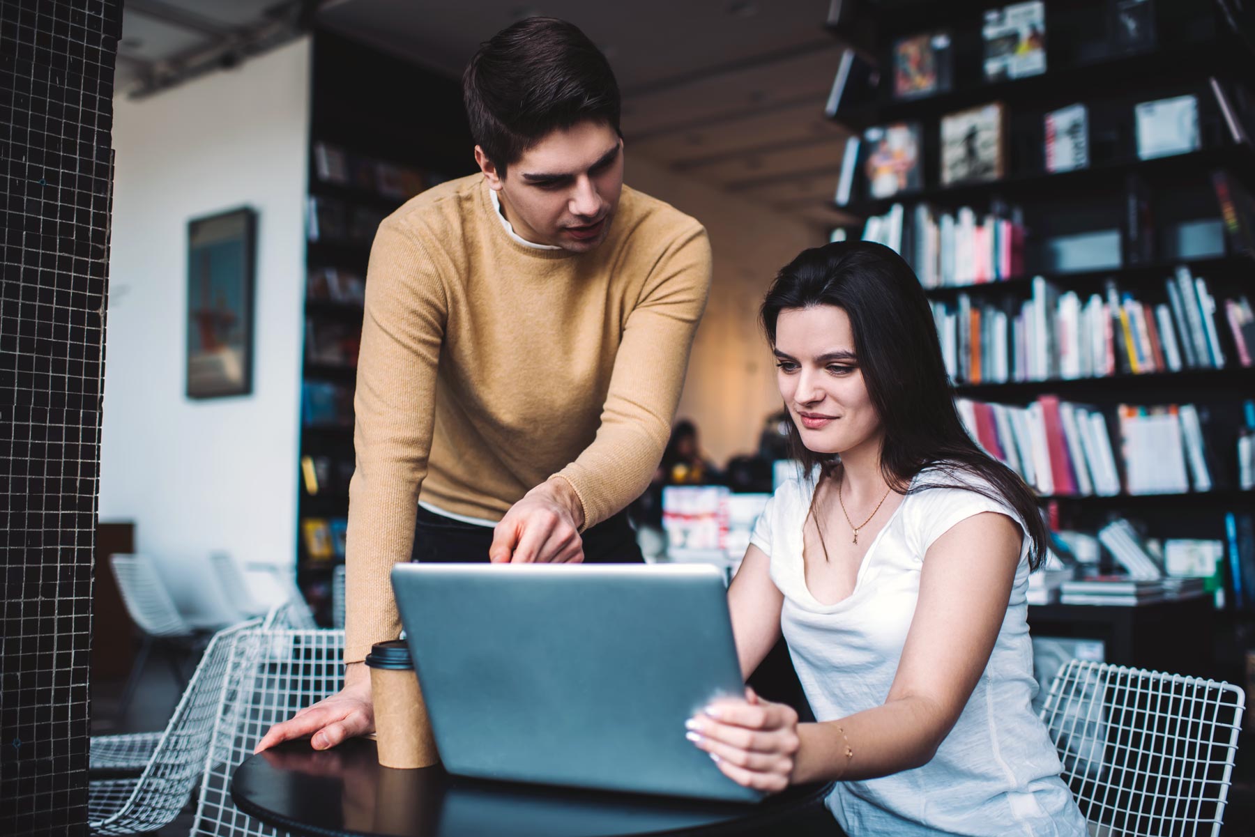 Focused young coworkers checking information on laptop